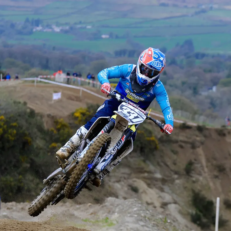 Glenn McCormick in the air on a motocross bike, wearing a blue race top