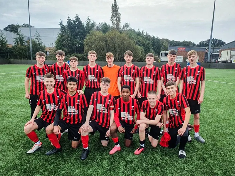 A Grove United FC youth team lined up in red and black stripes with the Colin Graham Residential logo on the front
